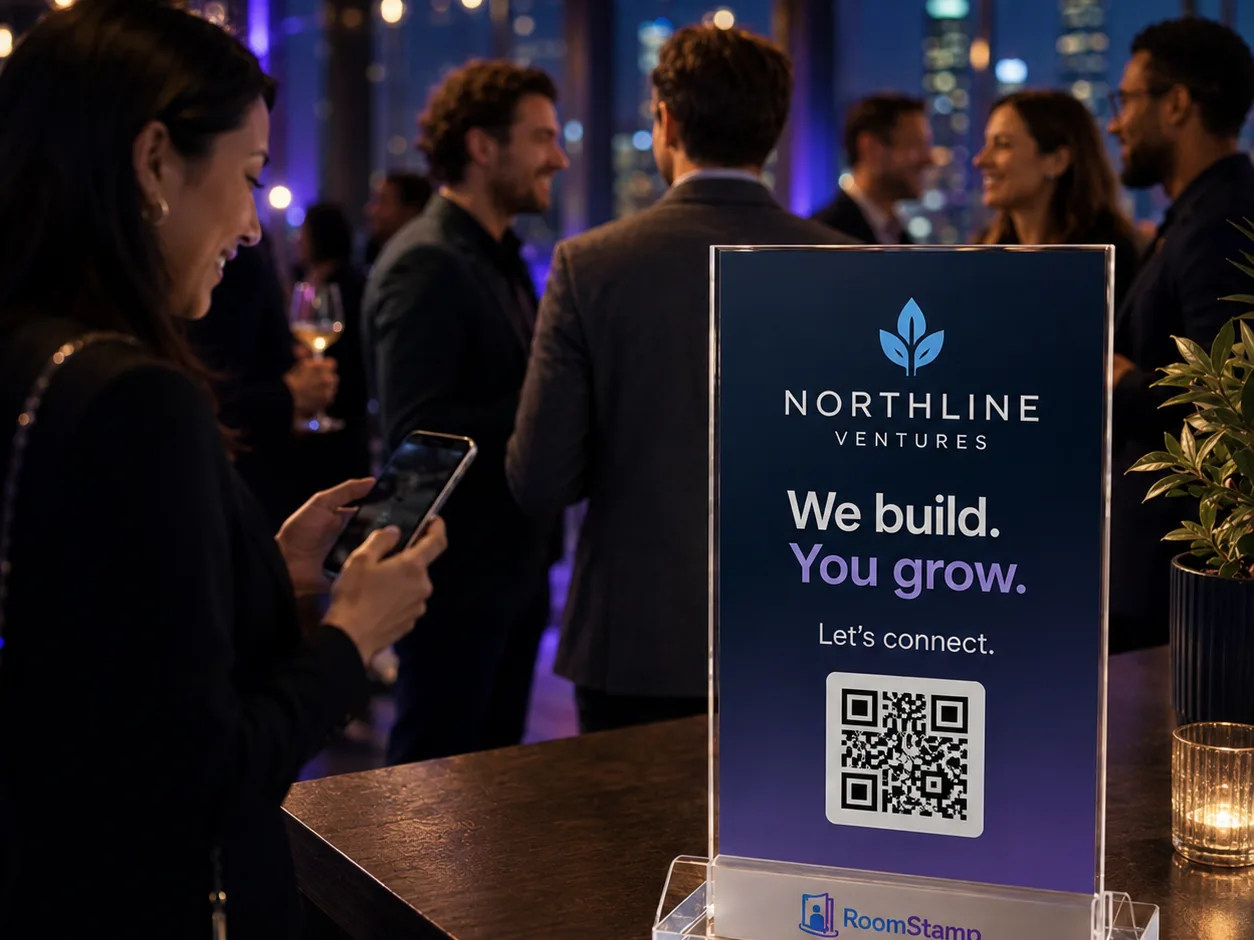 A branded RoomStamp display on a cocktail table at a networking event with people mingling in the background.